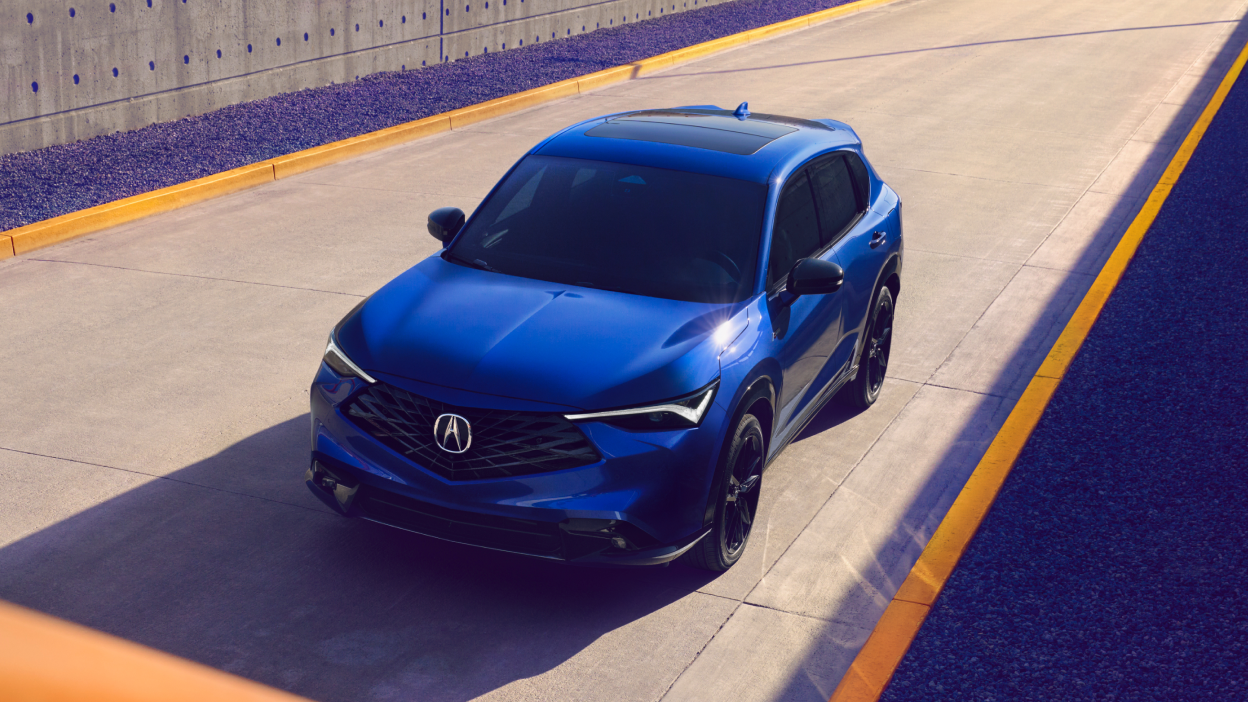 A blue 2025 Acura ADX is on an empty highway road.
