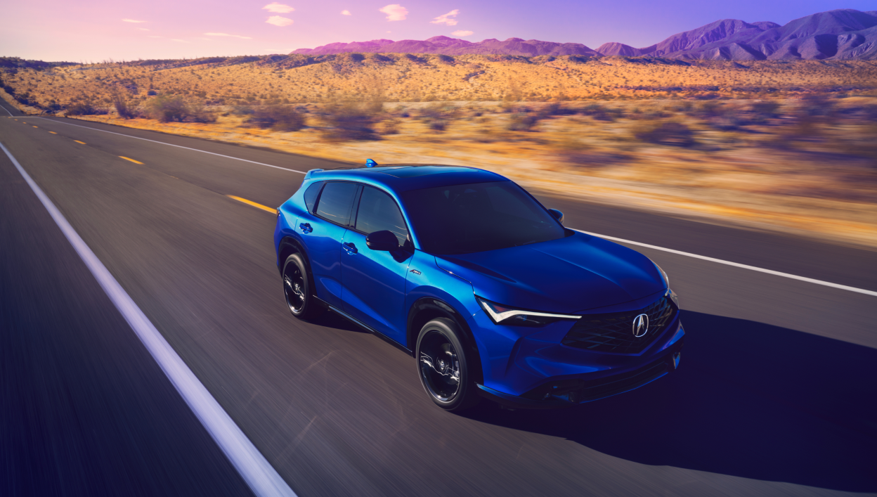 A blue 2025 Acura ADX is driving through the road on a dry desert grassland. 