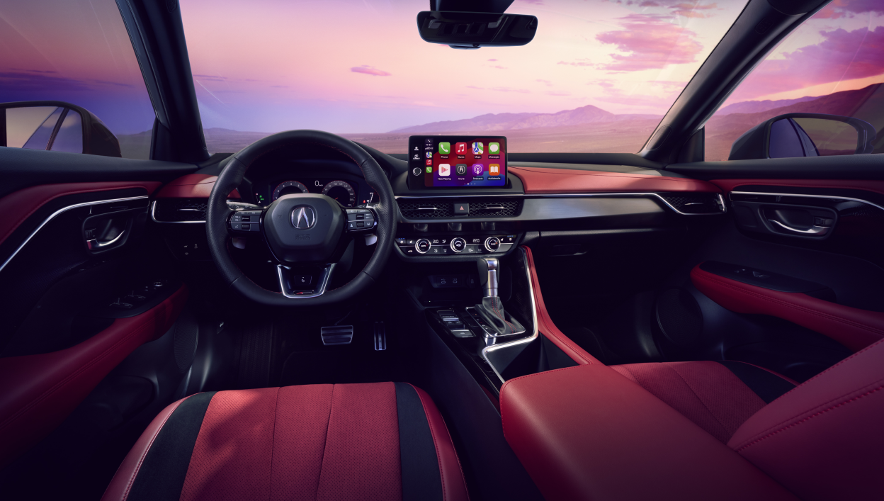 An interior shot of the 2025 Acura ADX revealing the steering wheel, the dashborad and a mountainous view with pink hues in the sky. 