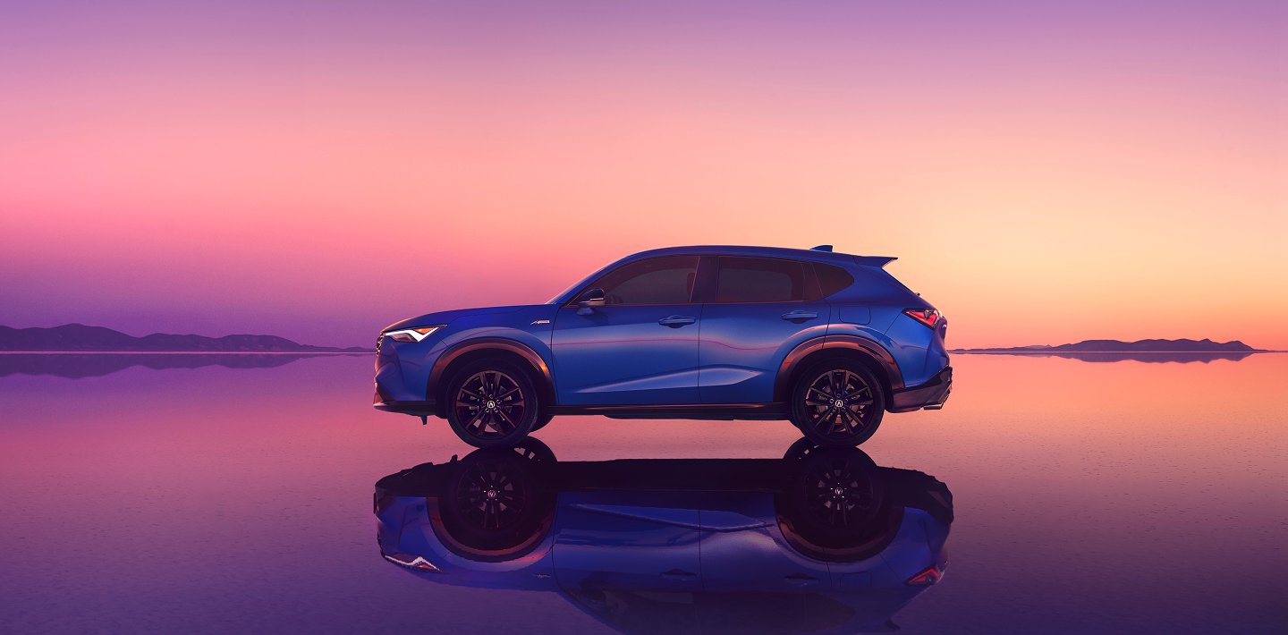 Side-view of an Acura ADX with a pink sunset in the background.