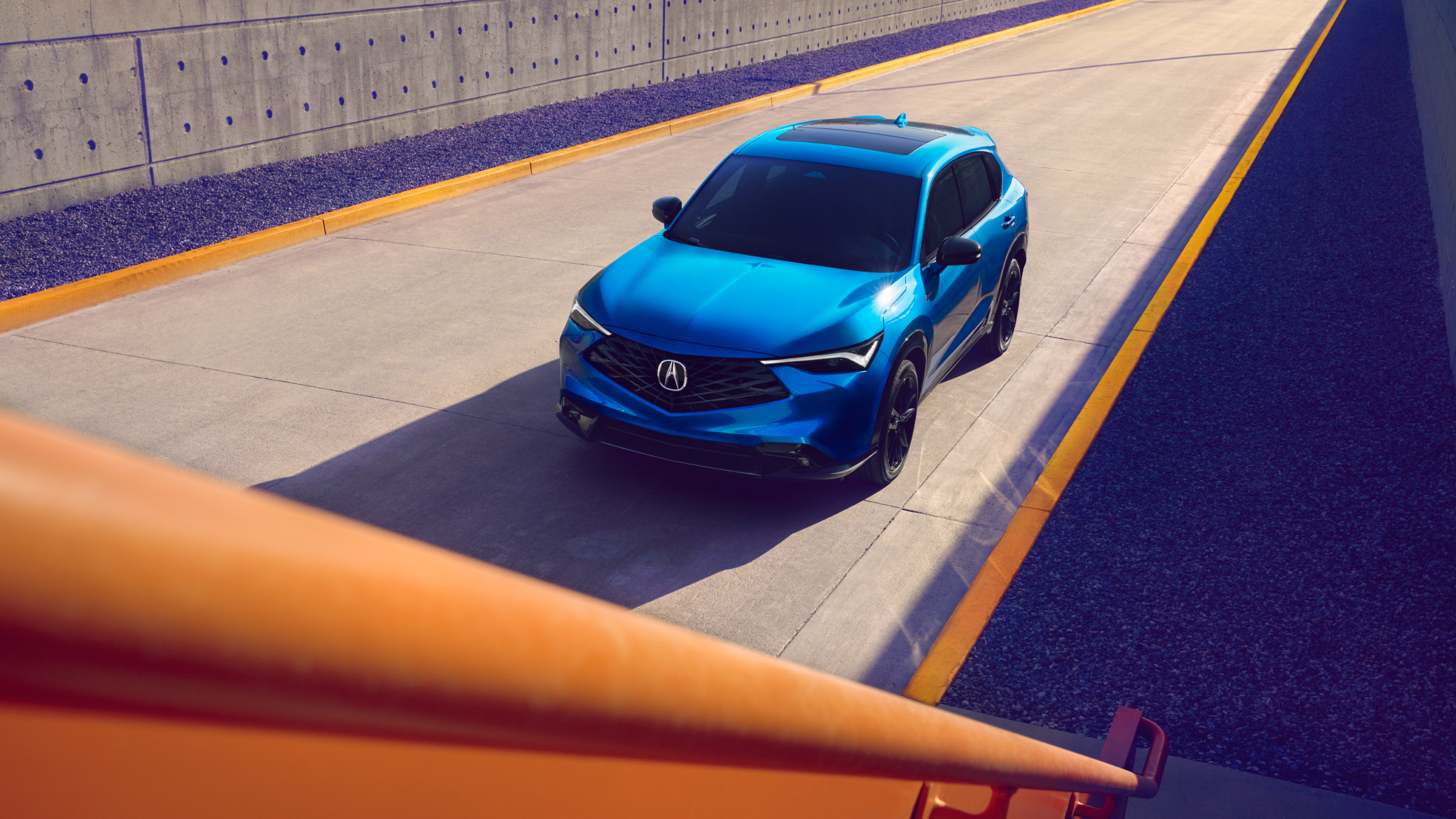 Overhead wide-shot of a blue Acura ADX on a road. 