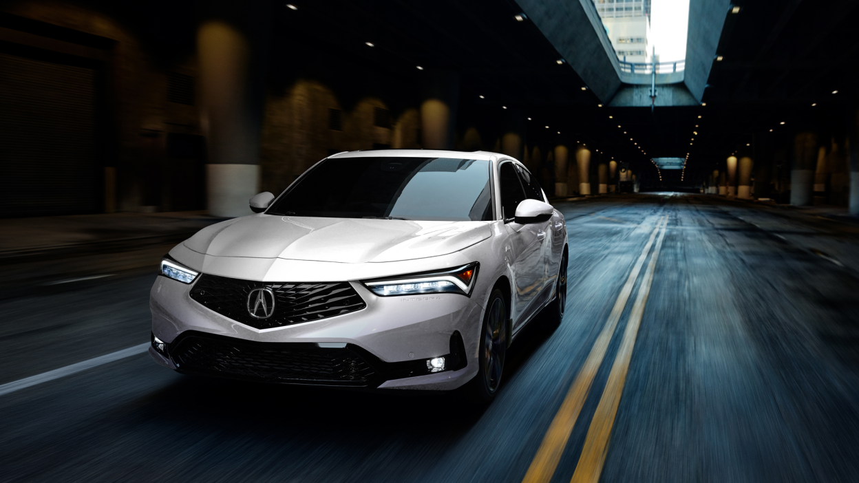 3/4 front view of white Integra driving in an empty underground expressway.
