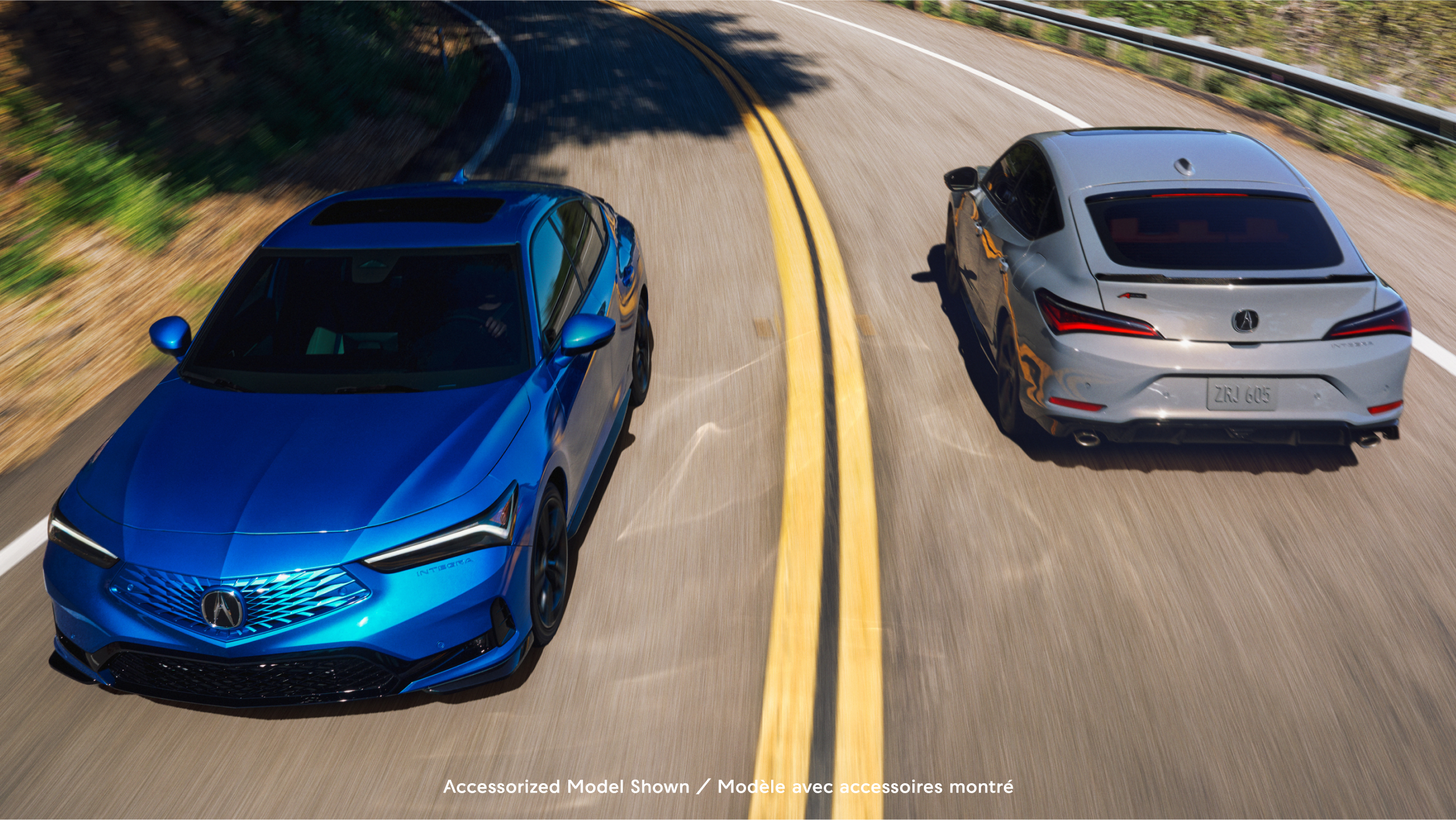 Two 2023 Integra models, one front with LED lights on, second rear-facing with male leaning against vehicle