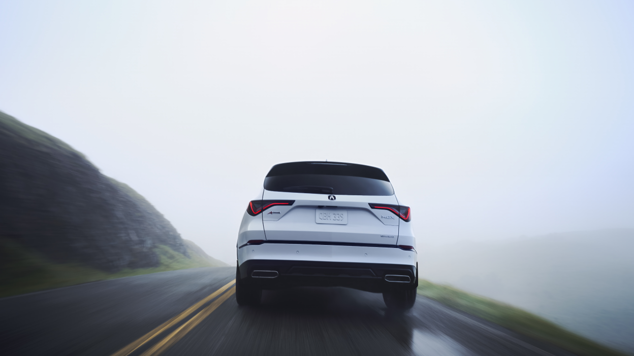A grey MDX driving through an underpass on a city street.
