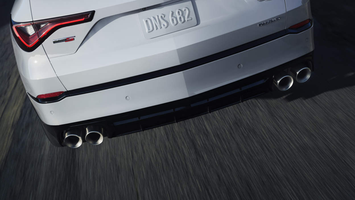 A red MDX taking a corner in the wilderness.