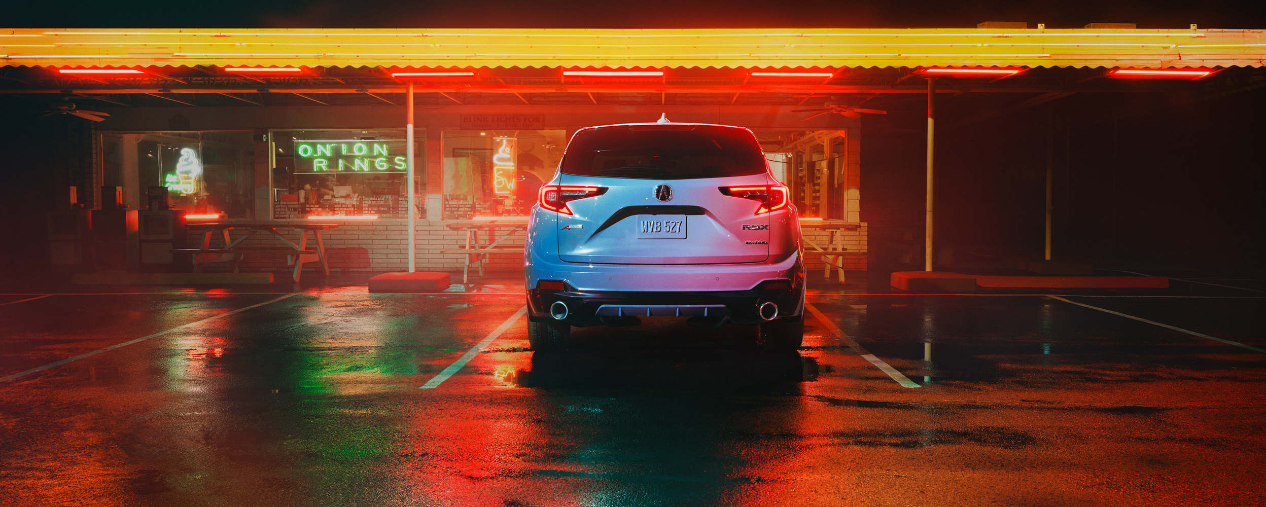 3/4 front view of blue RDX driving on dirt road. 