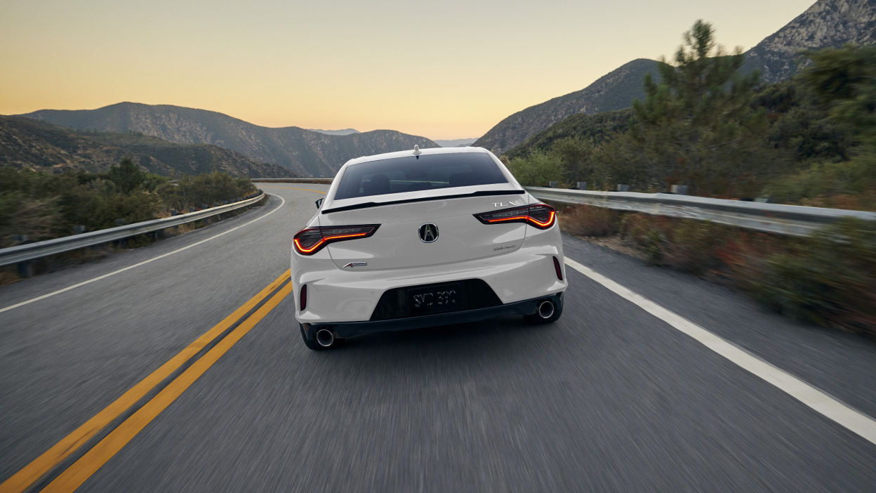 A white TLX in a darkly-lit warehouse.