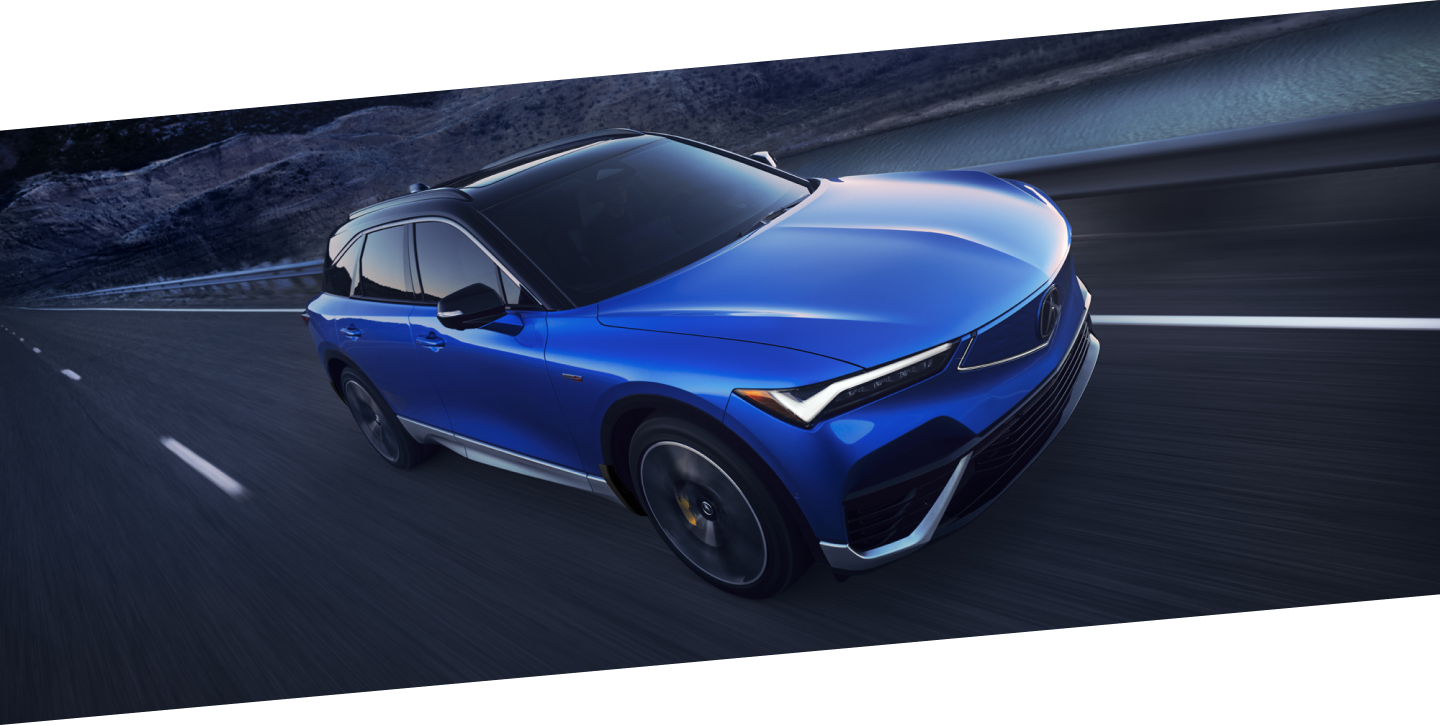 3/4 bird’s eye front view of blue ZDX driving on desert highway at dusk.