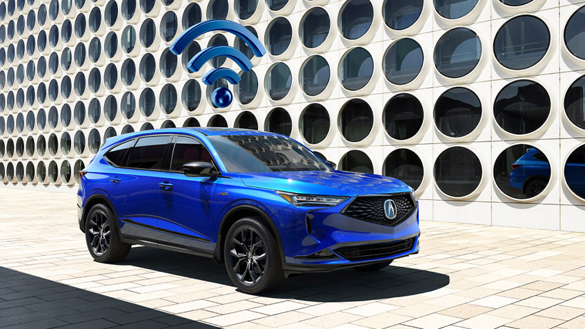 A blue wifi icon floating above a blue Acura MDX parked in front of a futuristic building. // Une icône wifi bleue flottant au-dessus d'un Acura MDX bleu stationné devant un bâtiment futuriste.